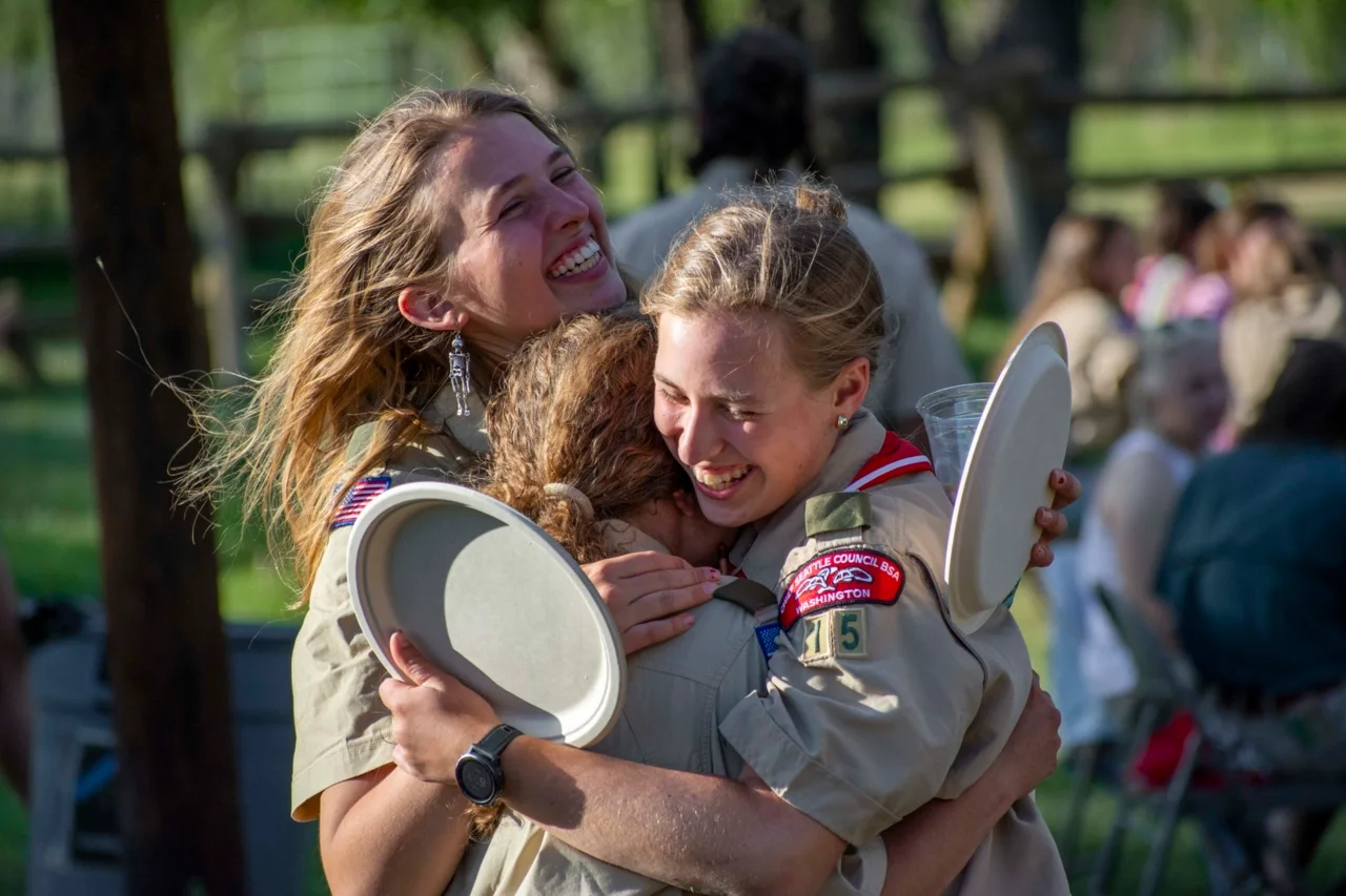 Scouting participants celebrate together while carrying plates at a banquet