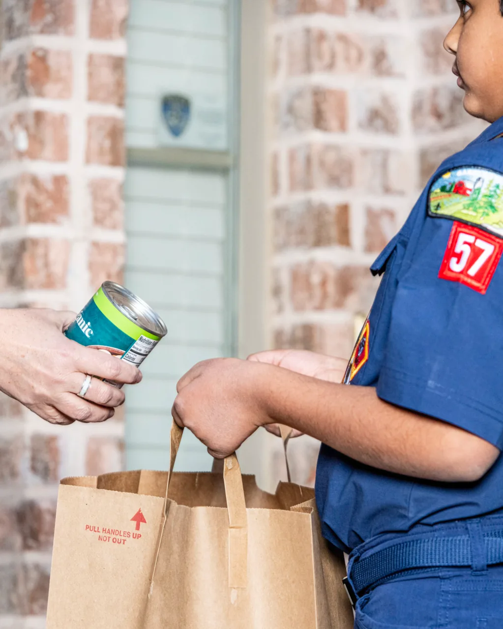 A Scout receives a donated food item for a collection