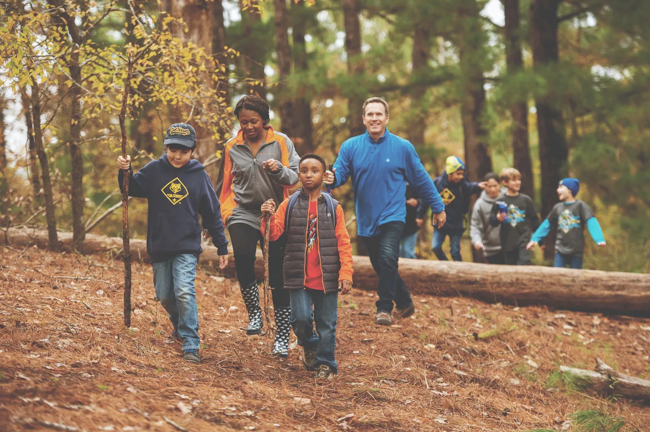Cub Scouts and their adult leaders hike together through the woods
