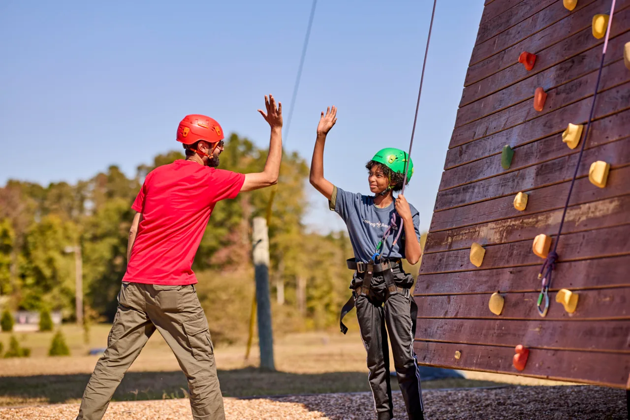 Two Scouts celebrate after completing a climbing challenge